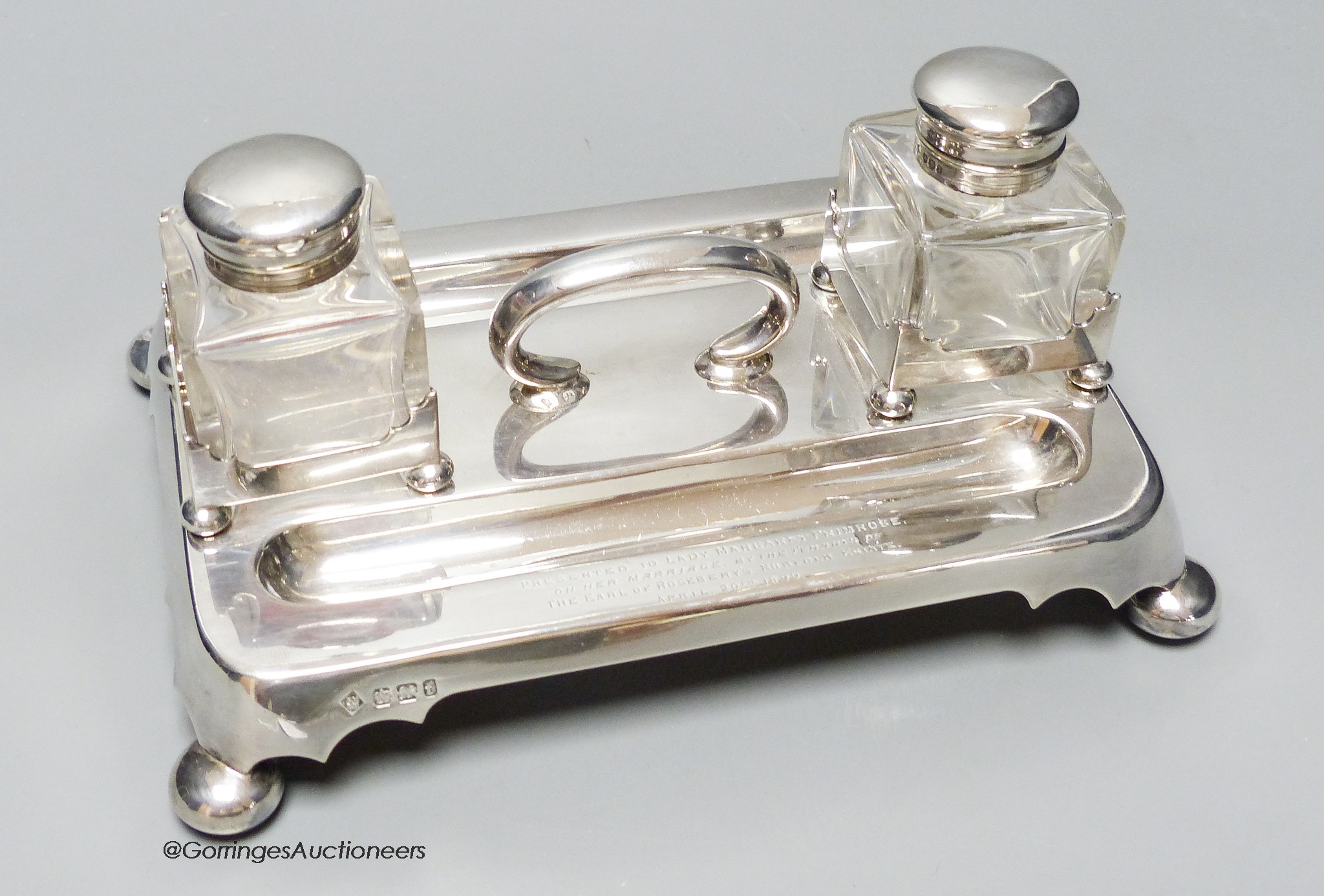 A late Victorian silver inkstand, with handle, pen recesses and two mounted glass wells, on bun feet, with engraved presentation inscription to Lady Margaret Primrose, on the occasion of her marriage, Martin, Hall & Co,